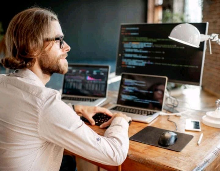 Freelancer cybersecurity risks USA concept showing a remote worker using multiple devices with client data on screen, highlighting data protection and online security risks